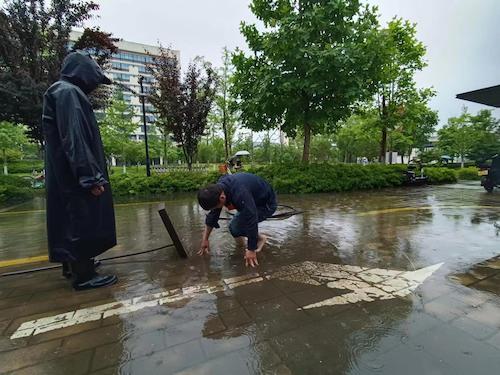 员工冒雨对下水道进行疏通1 员工冒雨对下水道进行疏通1
